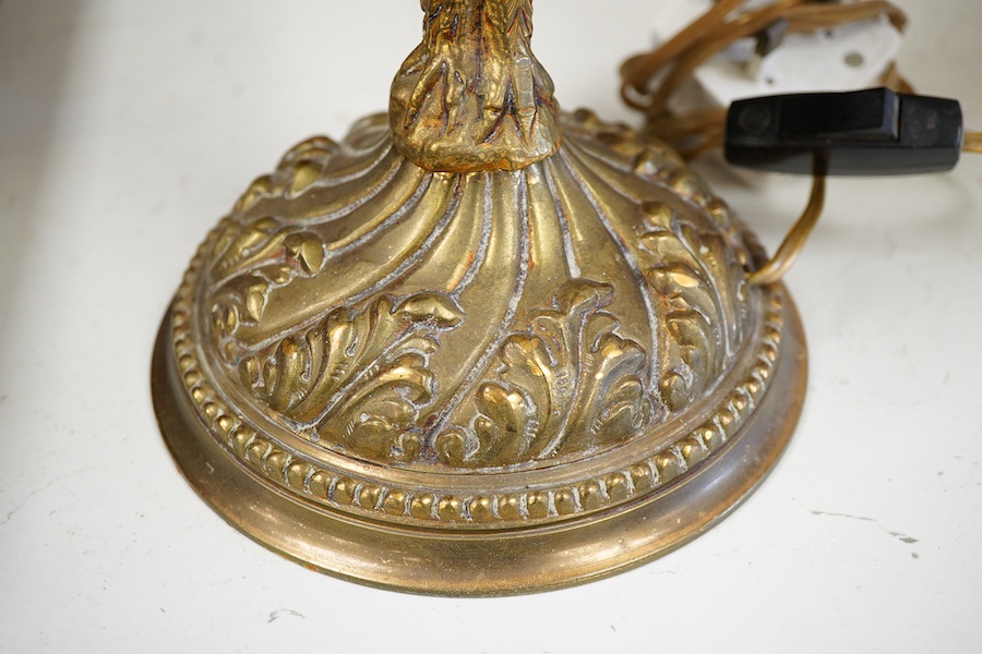 A brass three light table lamp with green toleware shade, another similar table lamp and a brass glass shaded lamp with a putti riding on the back of an eagle, (3)